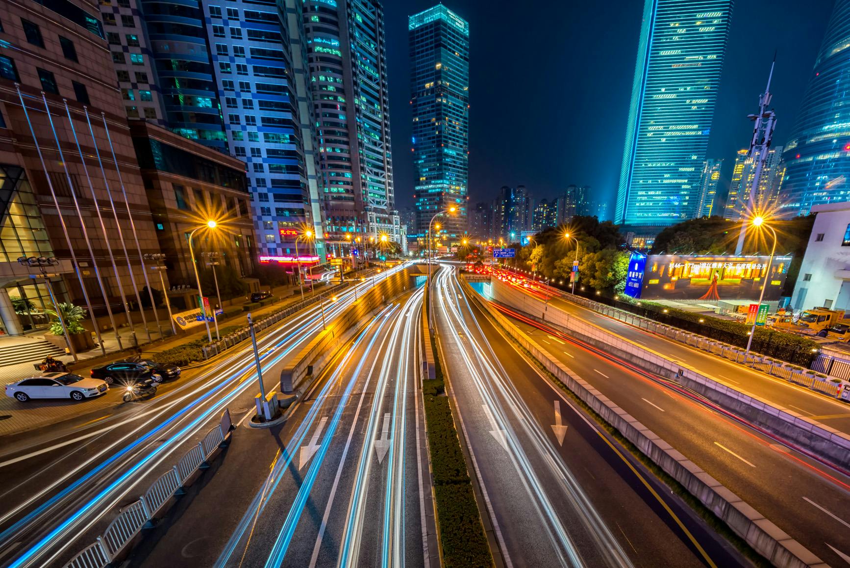 Photo by Peng LIU: Timelapse photography of vehicle on concrete road near in high rise building during nighttime